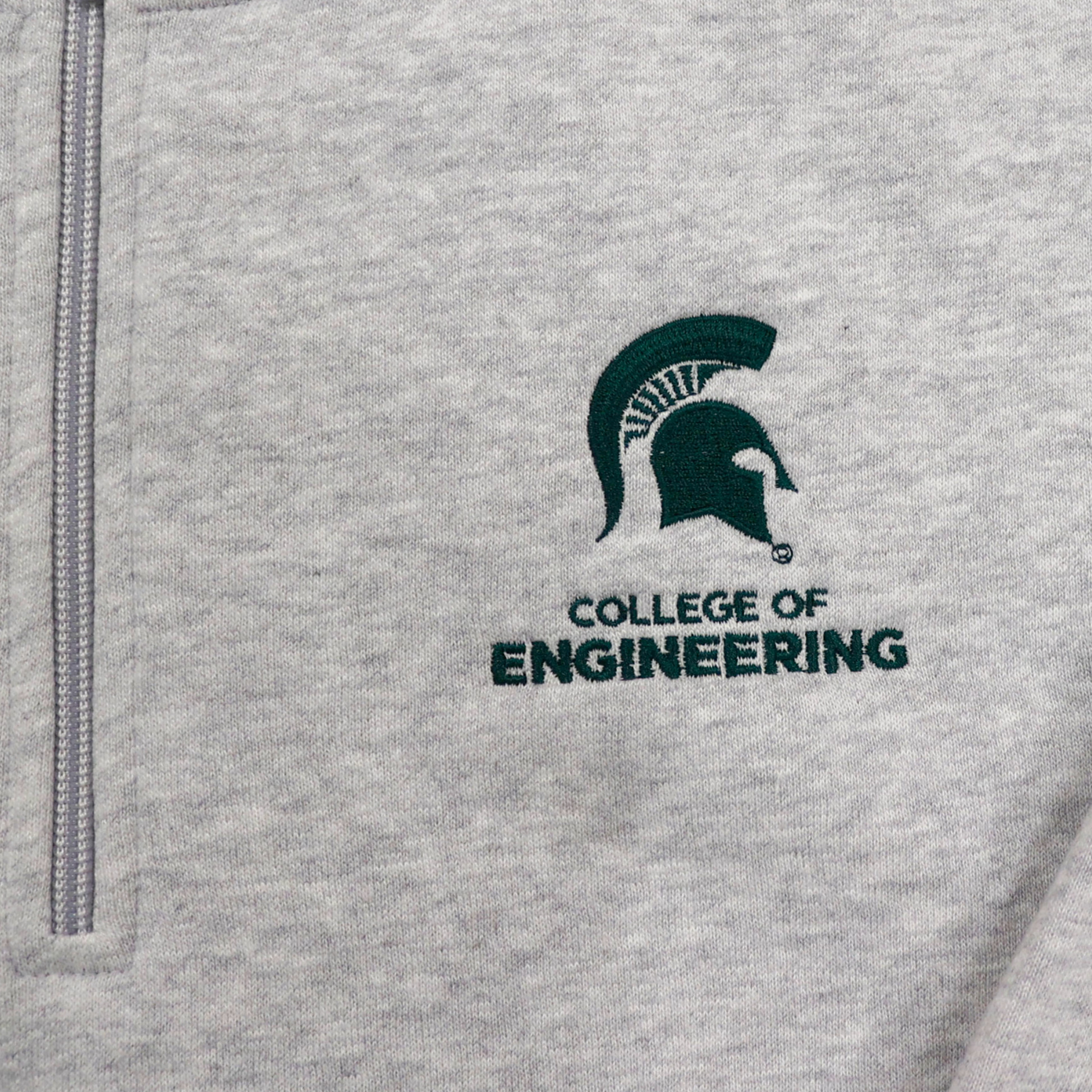 Close up of the chest logo on a heather gray quarter-zip sweatshirt. The logo is a green embroidered Spartan Helmet logo with "College of Engineering" written underneath in green.