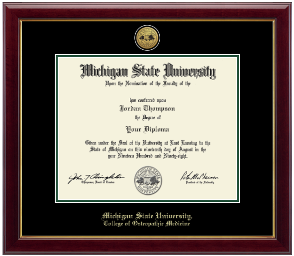 Framed Michigan State University diploma in a dark wood frame with a gold inner edge. The matte is black with a green inner border surrounding the diploma. Michigan State Seal is at the top of matte and is gold engraved. 'Michigan State University' is inscribed in gold at the bottom of the frame. Below Michigan State University is 'College of Osteopathic Medicine'.