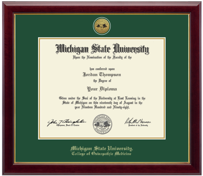 Framed Michigan State University diploma in a dark wood frame with a gold inner edge. The matte is tartan green with a gold inner border surrounding the diploma. Michigan State seal is at the top of matte and is gold engraved. "Michigan State University" is inscribed in gold at the bottom of the frame. Below Michigan State University is "College of Osteopathic Medicine."