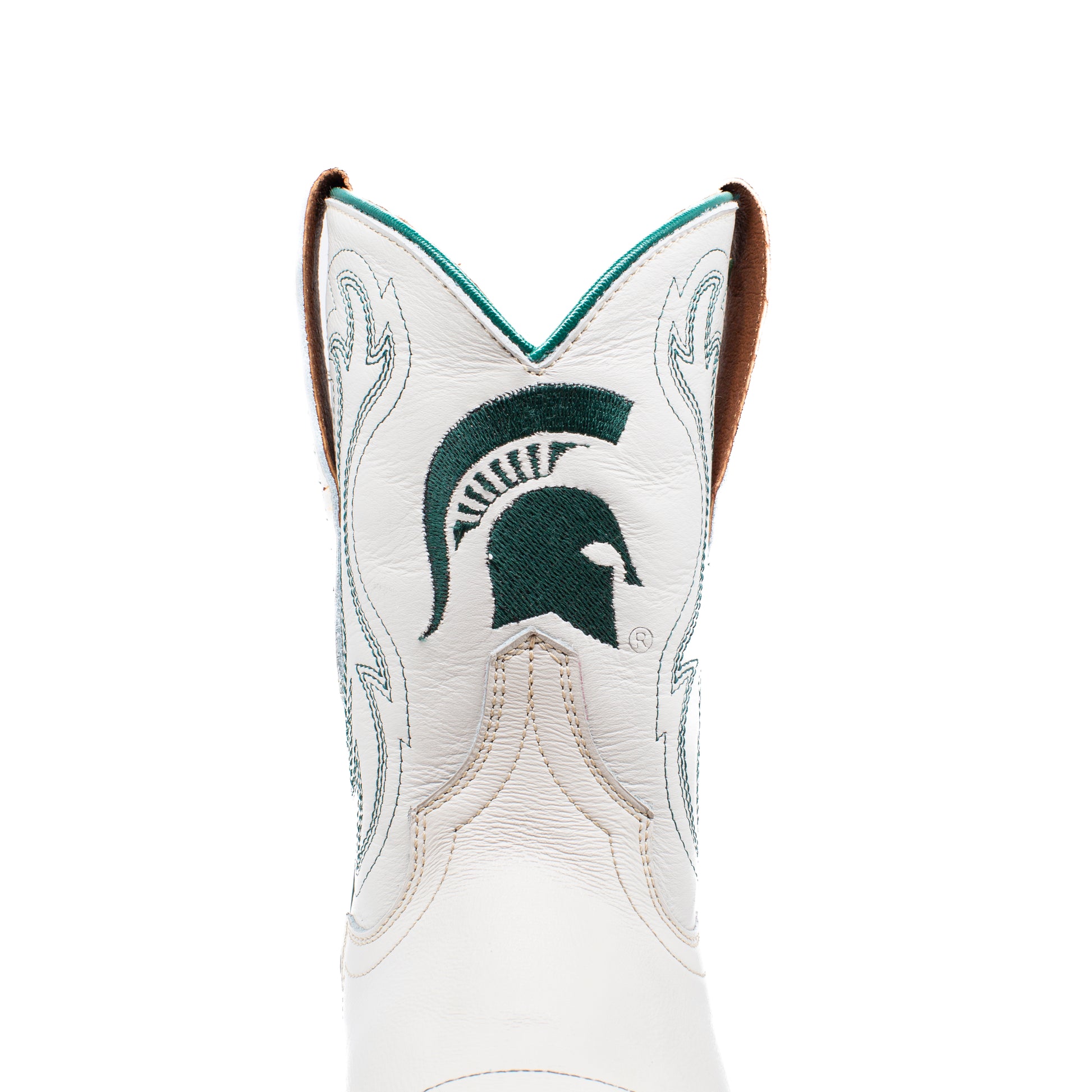 A close-up of a white leather cowboy boot featuring the Michigan State University Spartan logo embroidered in dark green on the shaft, with light green western-style stitching and a brown pull tab.