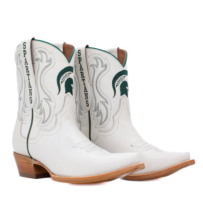 A pair of white leather cowboy boots featuring the Michigan State Spartans logo and 'SPARTANS' text on the shaft, with green and gray detailing and brown stacked heels.