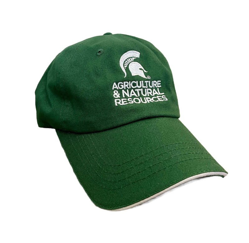 Forest green baseball cap. Centered on the front is white embroidery of a Spartan helmet. Below the helmet is all-caps white text on three lines reading “Agriculture & Natural Resources.”  