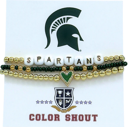 Three bracelets stacked together. The top bracelet is gold with white beads that spell out "Spartans." The middle bracelet is green with gold enamel. The last bracelet is gold with a green heart charm in the middle. 