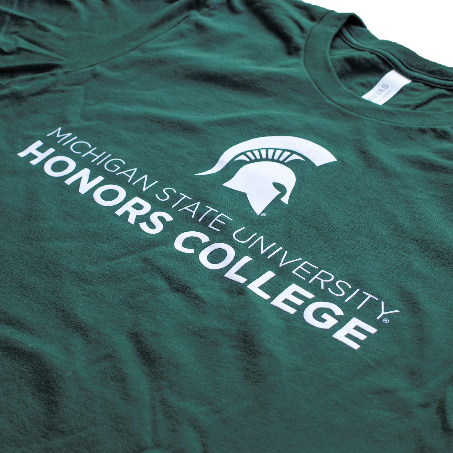 A forest green tee shirt with a white MSU Spartan Helmet logo. Underneath the logo, in white, is the text "Michigan State University Honors College."