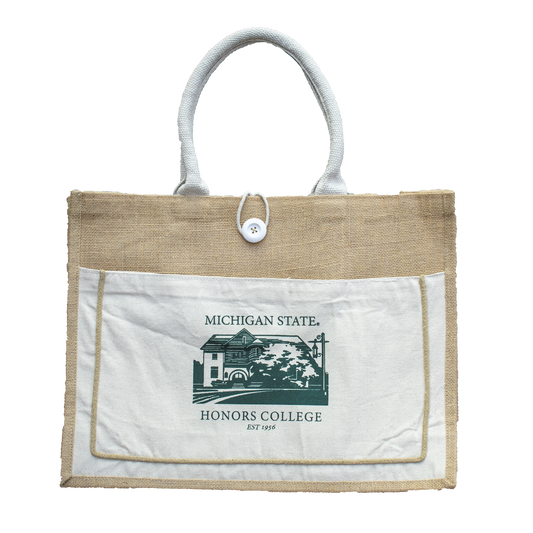 A tan and white tote bag made of jute and canvas material. On the side of the tote in green is a graphic of the Michigan State Honors College building. Above and below the image is the text that reads "Michigan State Honors College Est. 1956."