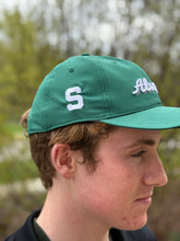 Side view of dark green alumni hat, showing the white embroidered block S.