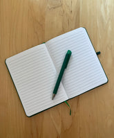 Open notebook with lined pages and a green pen.