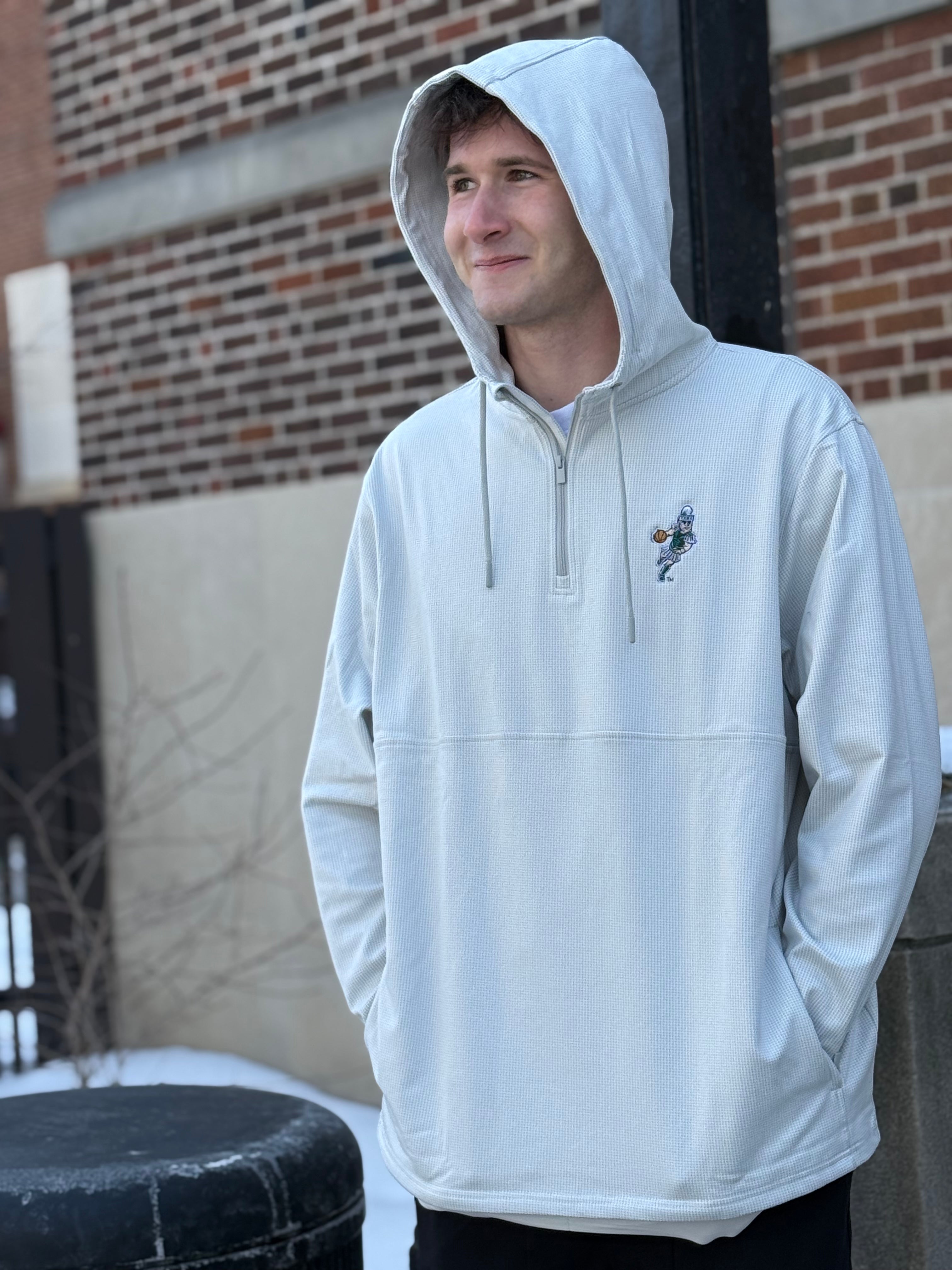 Man standing outdoors, wearing a white quarter-zip drawstring hoodie with an embroidered basketball Sparty logo on the upper left chest and two pockets on either side. 