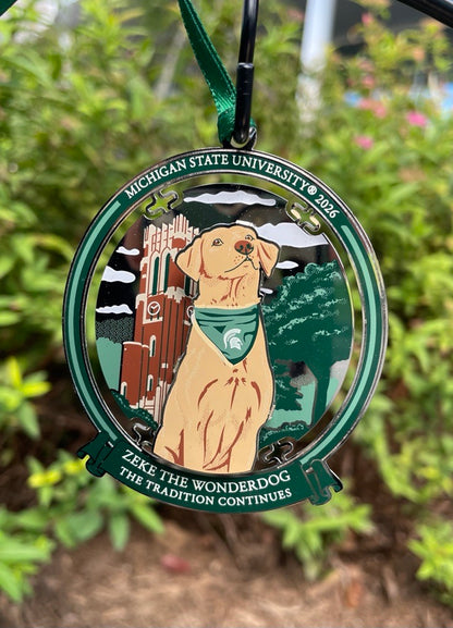 Circular metal ornament showing Zeke the Wonderdog in front of Beaumont Tower surrounded by trees. The bottom reads "Zeke the Wonderdog The Tradition Continues"