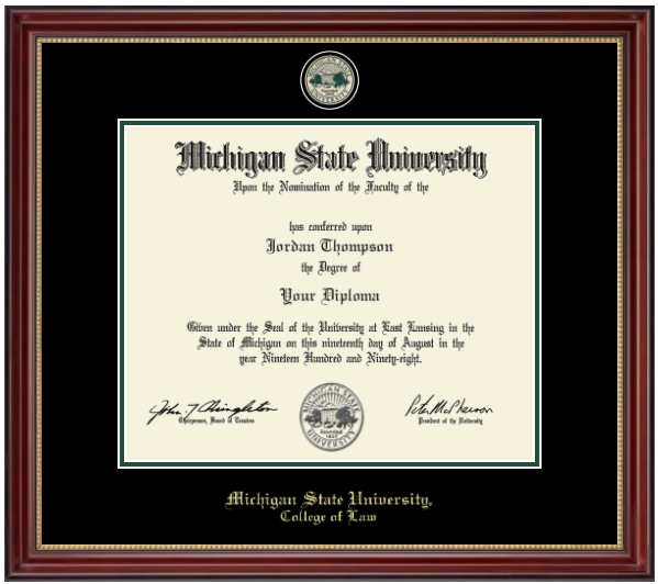 The diploma is enclosed in a dark wood frame with a black matte with green accents and gold trim. In gold cursive letters "Michigan State University" at bottom. Below in gold cursive letters "College of Law." Top of matting is gold engraved Michigan State University seal. 