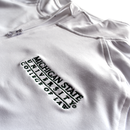 Close-up of the embroidered forest green Michigan State University College of Law wordmark logo on the left chest of a white jacket.