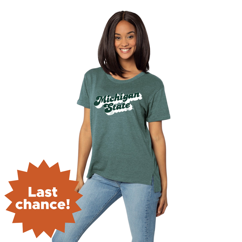 Green t-shirt with 'Michigan State' written in white on the front, worn by a person also wearing light blue jeans. An orange starburst in the bottom left corner reads 'Last chance!