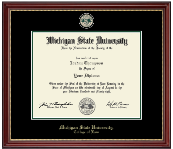The diploma is enclosed in a dark wood frame with a black matte with green accents and gold trim. In gold cursive letters "Michigan State University" at bottom. Below in gold cursive letters "College of Law." Top of matting is gold engraved Michigan State University seal. 