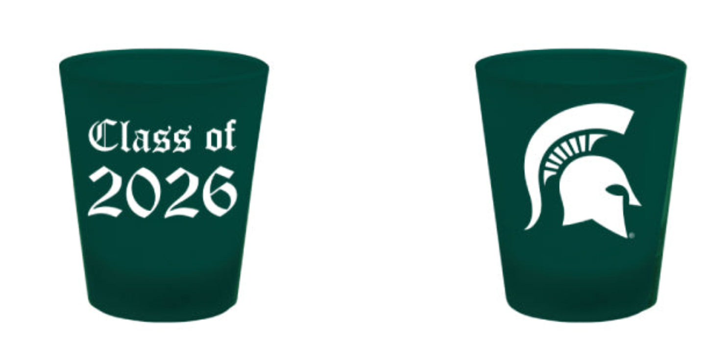 Two green shot glasses with white writing 'Class of 2026' and white Spartan Helmet logo. Shown on a white background.
