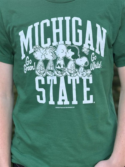 Close up of a green screen printed Michigan State University T-shirt featuring white text that reads 'Michigan State' with 'Go Green!' and 'Go White!' on each side. Below the text are Peanuts characters, including Charlie Brown, Snoopy, and friends.