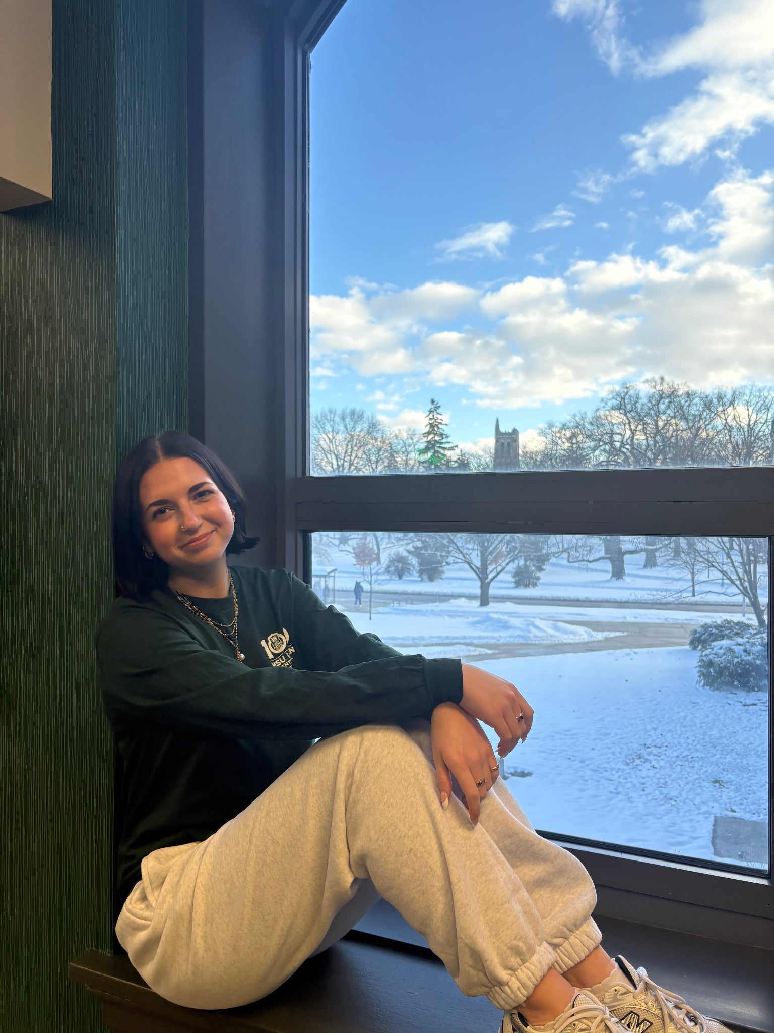 Women wearing dark green long sleeve shirt with screen printed text "100 MSU Union" on left chest.
