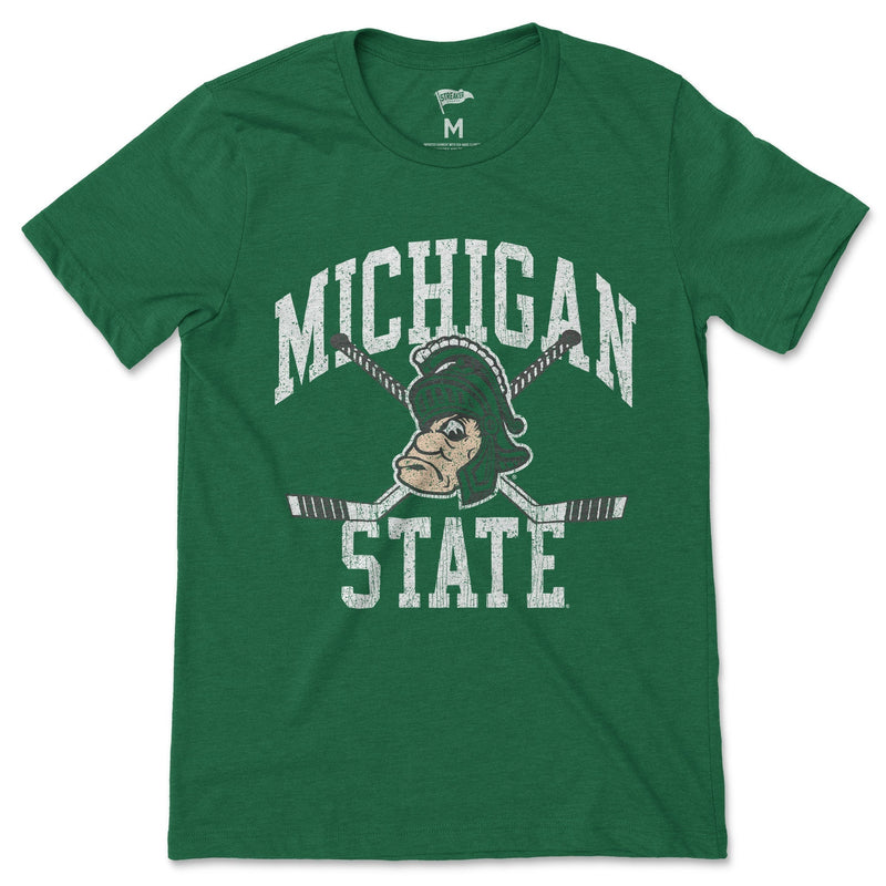 A green t-shirt with a Gruff Sparty logo over crossed hockey sticks between the words "Michigan State" in white.