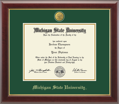 Framed Michigan State University diploma in a dark wood frame with a gold inner edge. The matte is tartan green with a gold inner border surrounding the diploma. Michigan State seal is at the top of matte and is gold engraved. "Michigan State University" is inscribed in gold at the bottom of the frame.