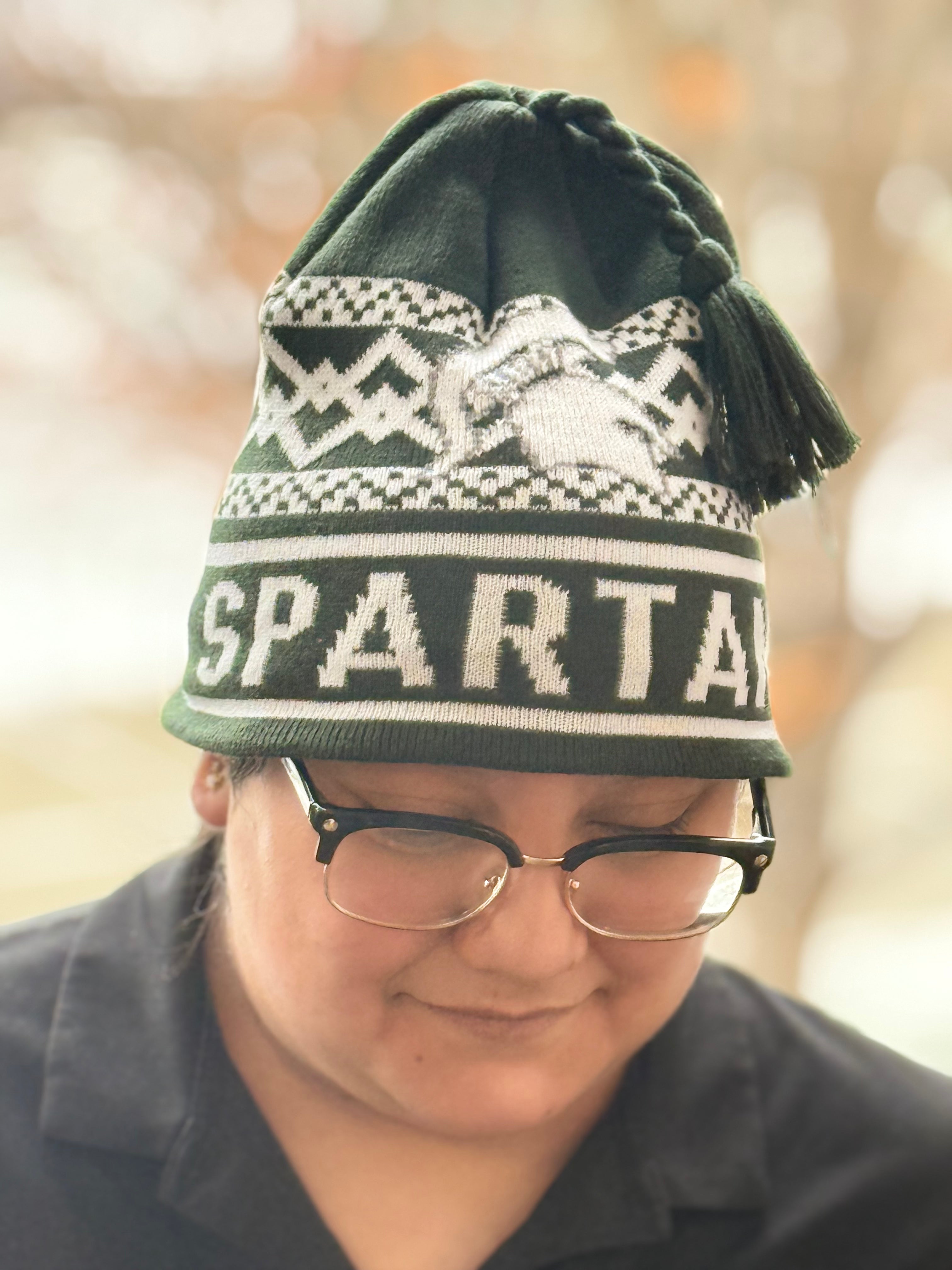 Green and white Michigan State Spartans knit beanie with tassel, featuring winter pattern, Spartan helmet graphic, and bold “SPARTANS” text across the cuff.