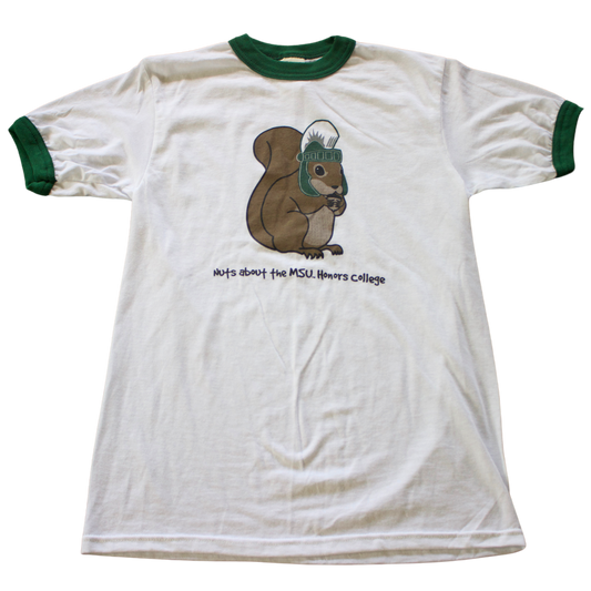 A white T-shirt with green trim on the collar and sleeves. The shirt features a cartoon image of a brown squirrel wearing a green MSU Spartan Helmet. Below the squirrel, black text reads: "Nuts about the MSU Honors College." 