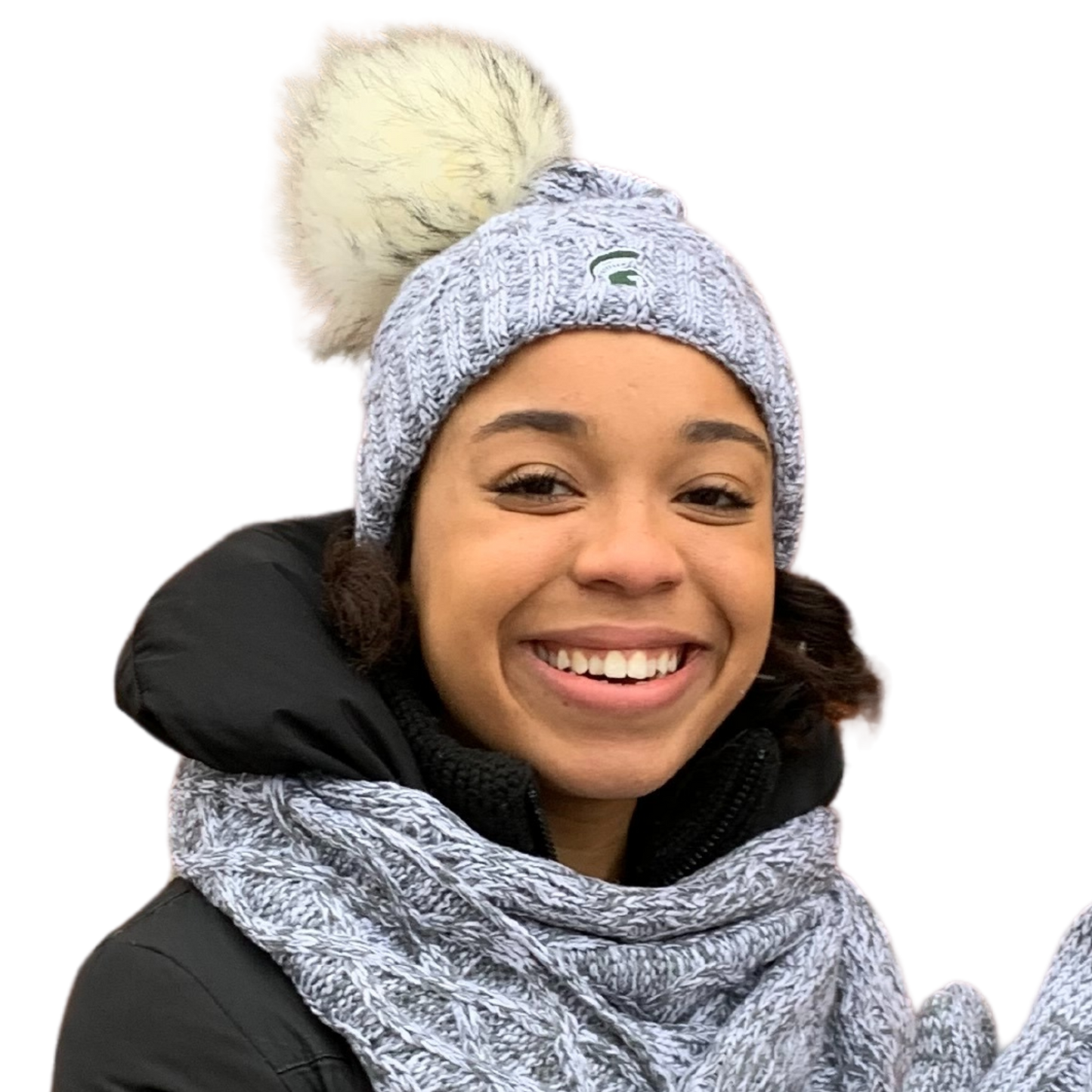 Close-up of a woman wearing a light gray knit beanie with an off-white and gray pom at the top. On the front is an embroidered green Spartan Helmet.