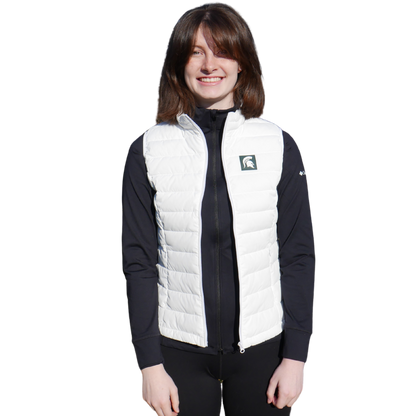 Woman facing forward wearing a white puffer vest that has a small green box with a white Spartan Helmet in it at left chest. 