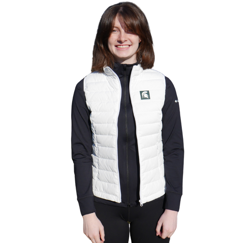 Woman facing forward wearing a white puffer vest that has a small green box with a white Spartan helmet in it at left chest. 