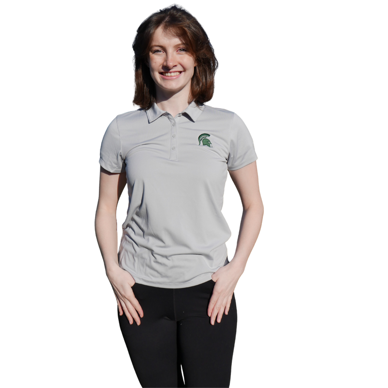 A woman wearing a gray women's Columbia polo with four-button placket, green Spartan helmet at left chest and Columbia on the left sleeve.