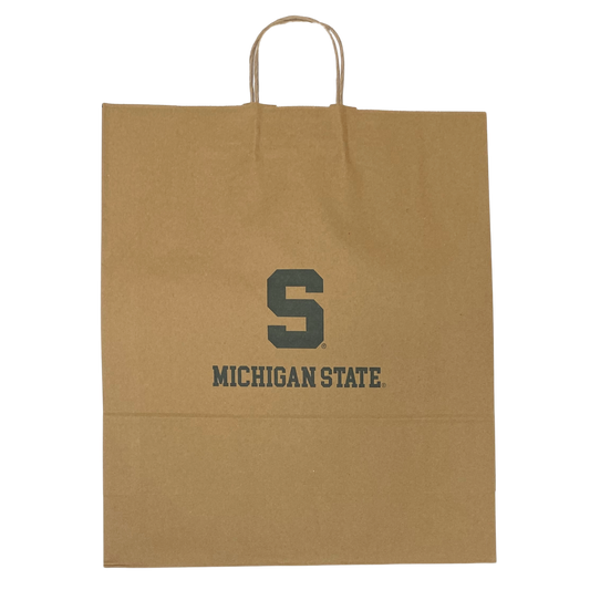 A brown heavy-weight kraft paper gift bag. It's 16 inches wide, 19 inches tall, and 6 inches deep. The bag features a green block S logo and the words "Michigan State" in a green collegiate font. At the top are thin brown handles made of twisted paper. 