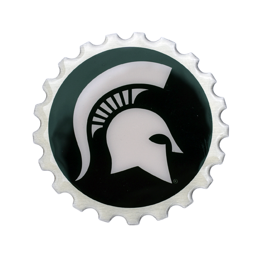Dark green circle with a large white Spartan Helmet logo in the center. The edges are scalloped and silver in color, giving the effect of a gear.