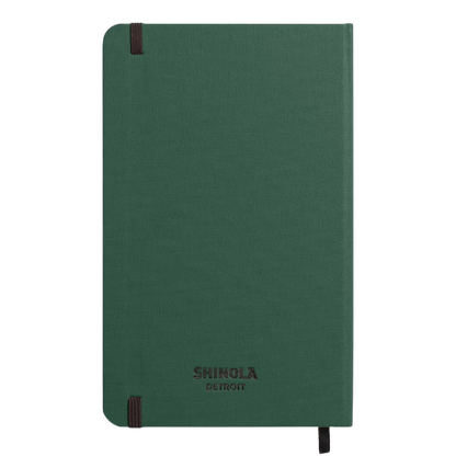 Back of hard linen green notebook with "Shinola Detroit" branding on a plain green back cover.