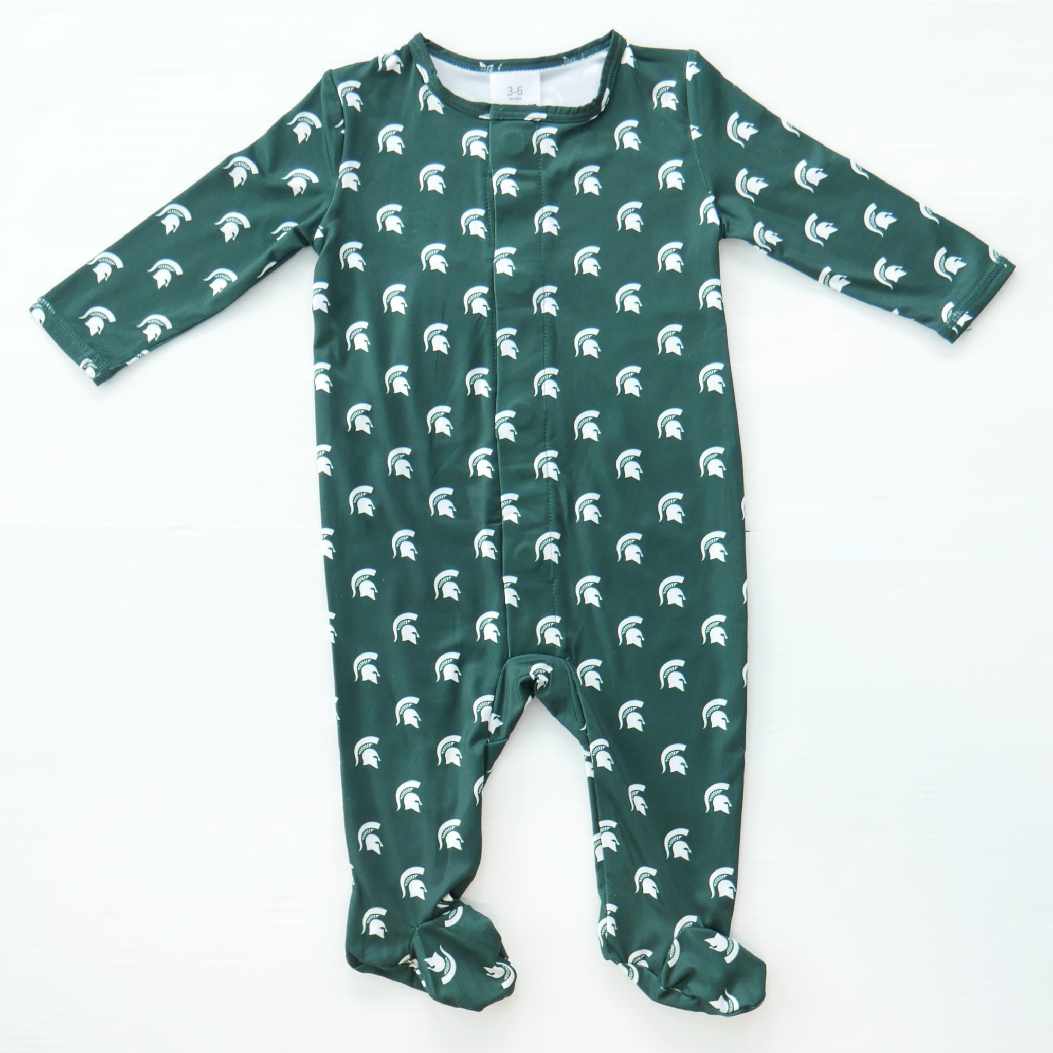 A green footie onesie with small Michigan State Spartan helmet logos scattered throughout the onesie in white. 