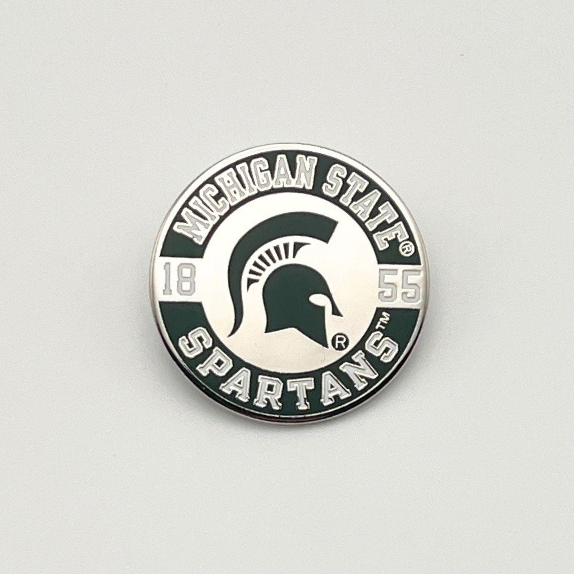 Michigan State Spartans lapel pin with a  green Spartan Helmet in the center, a curved "Michigan State" wordmark around the top, a curved "Spartans" wordmark, and the year 1855. 