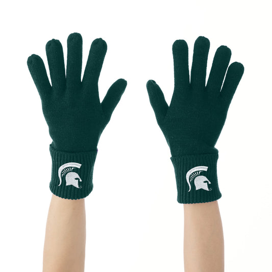 Pair of dark green Michigan State Spartans knit gloves shown on raised hands against a white background. Each glove features a soft knit construction with ribbed cuffs and an embroidered white Spartan helmet logo centered on the cuff.
