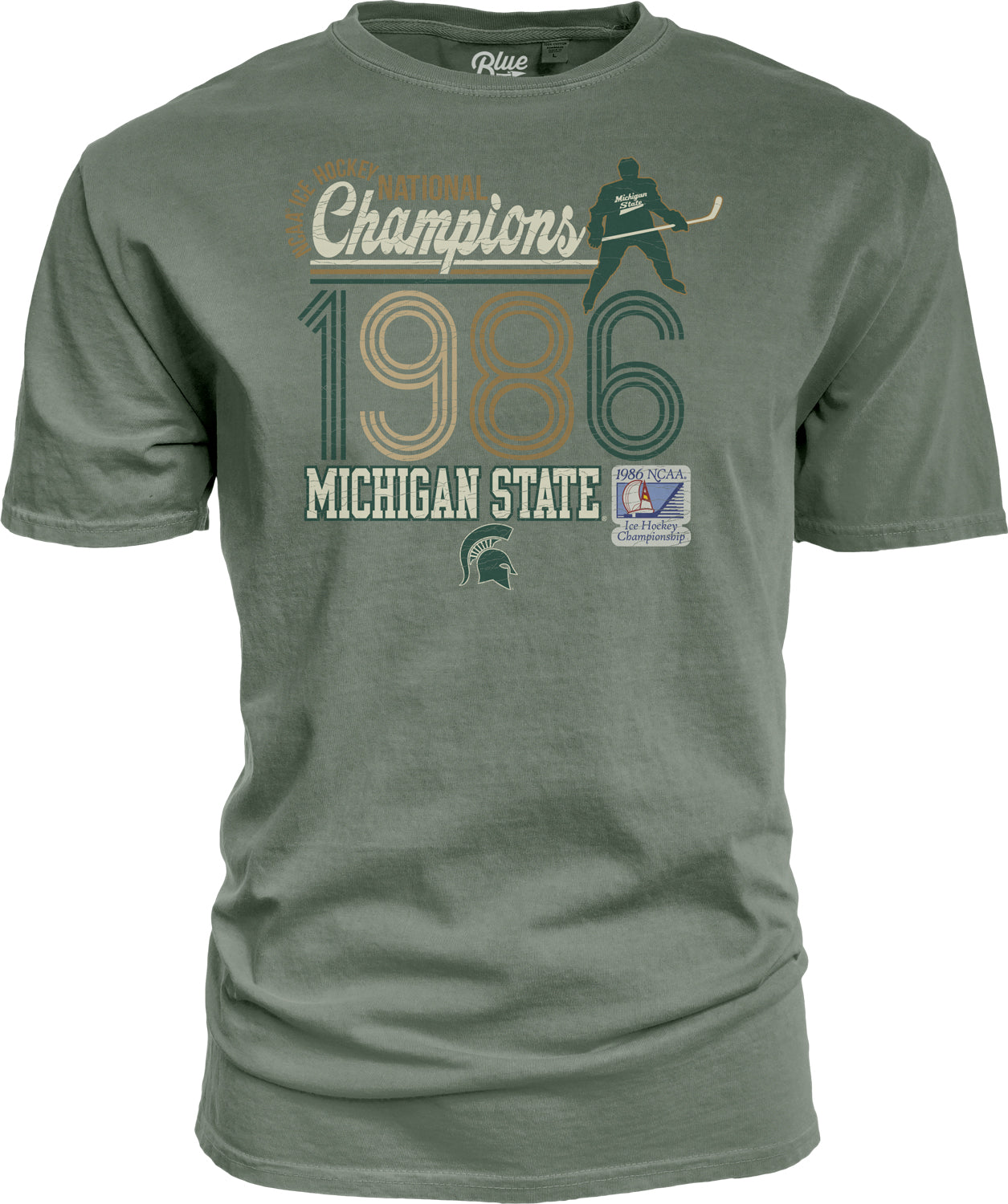 Green T-shirt with hockey themed graphics, "Champions 1986 Michigan State" text and the 1986 NCAA Ice Hockey Championship patch. Shown on a white background.