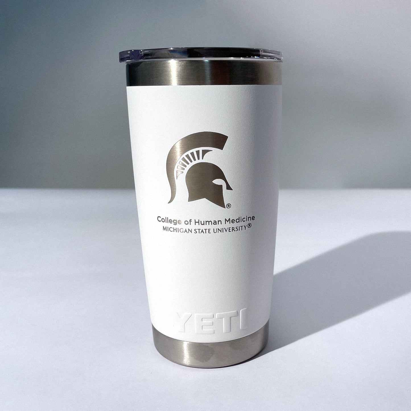 A white, 20 ounce beverage tumbler with a silver etched Spartan Helmet logo and the words "Michigan State University College of Human Medicine" below it.