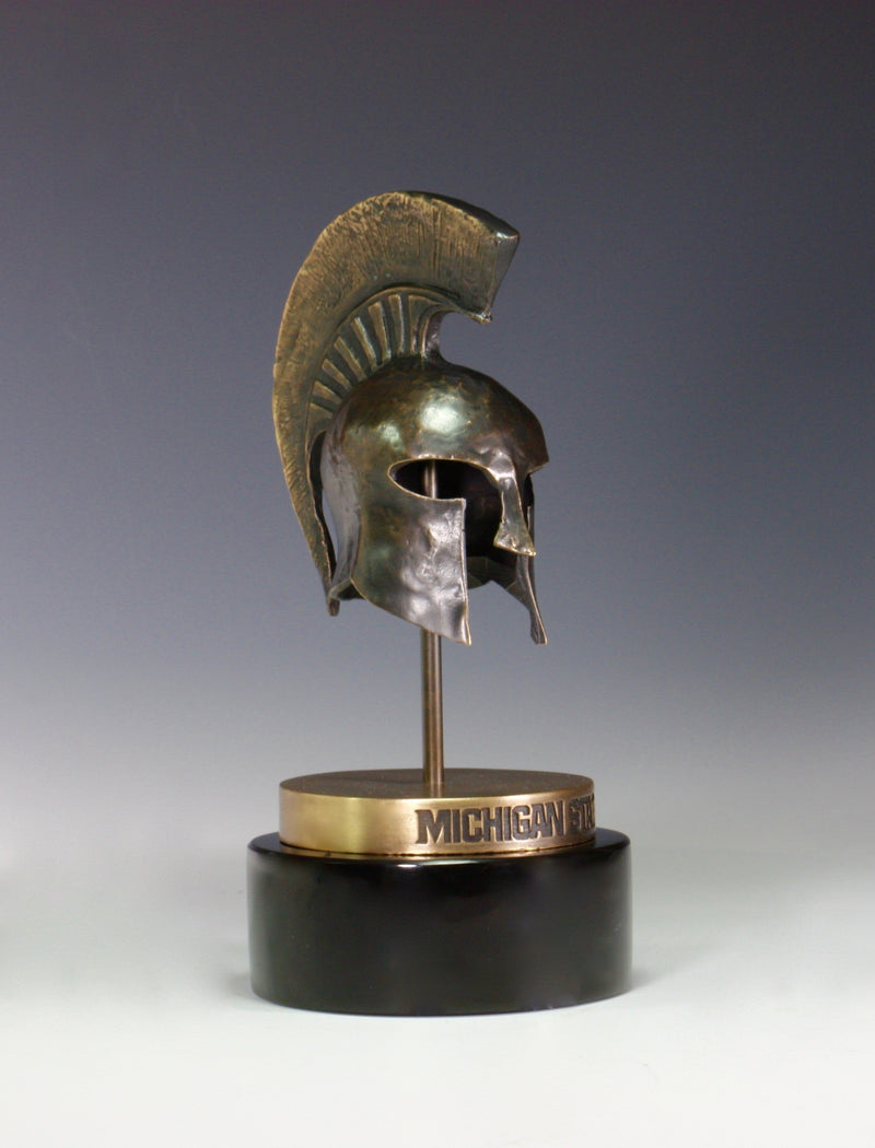 A bronze Spartan helmet statue on a black base.