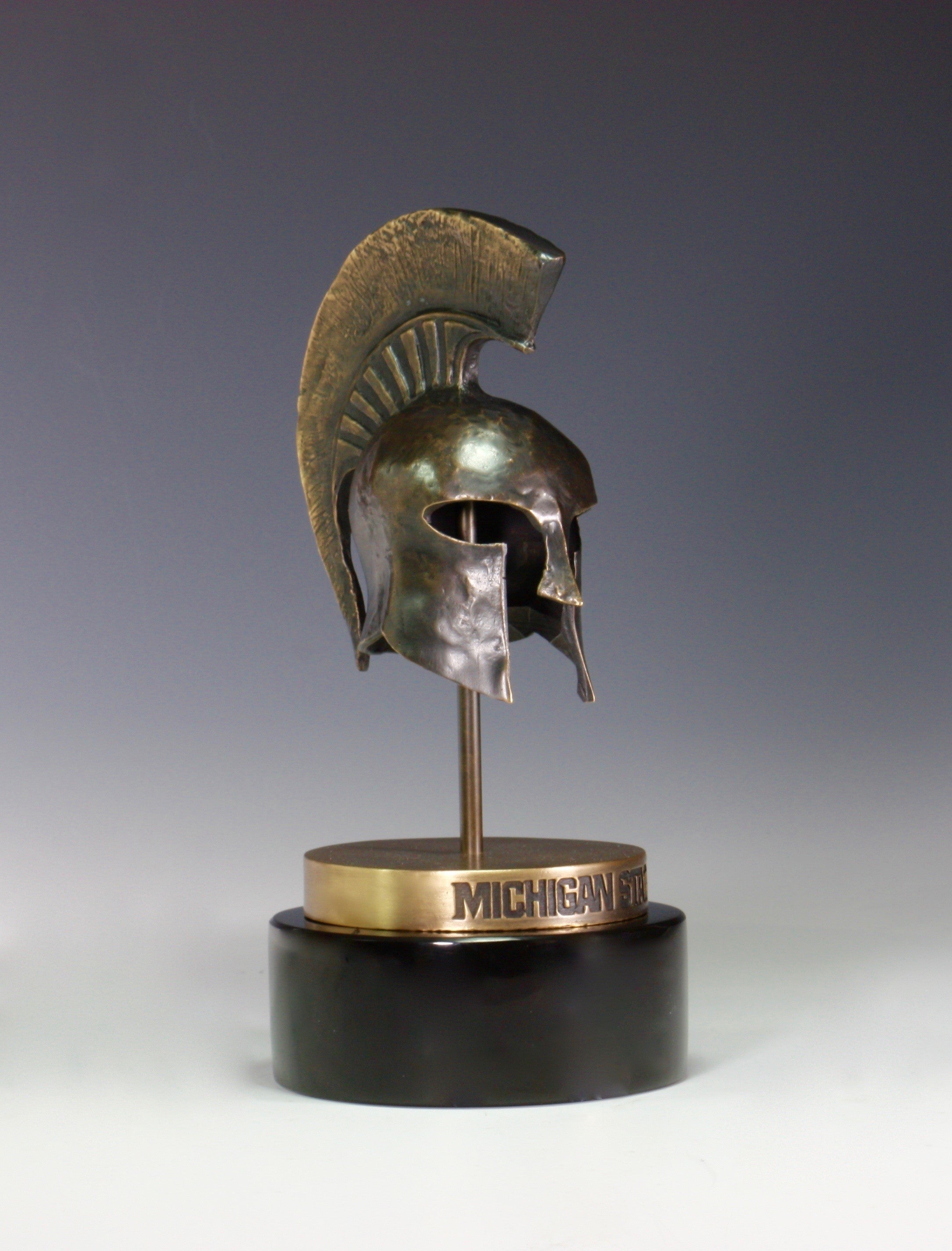 A bronze Spartan helmet statue on a black base.