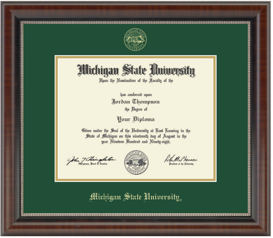 displayed in a dark wood frame with a tartan green matte and gold trim. 'Michigan State University' is printed at the bottom. At top is a gold embossed Michigan State University seal. 