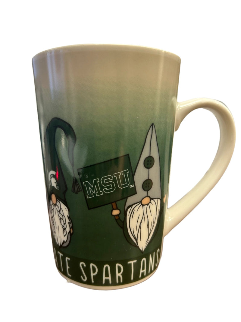 Ceramic mug that is green at the bottom and fades in a cream color. On bottom edge it says in white lettering' Michigan State Spartans' . In the middle of the mug are gnomes wearing various Michigan State colors. 