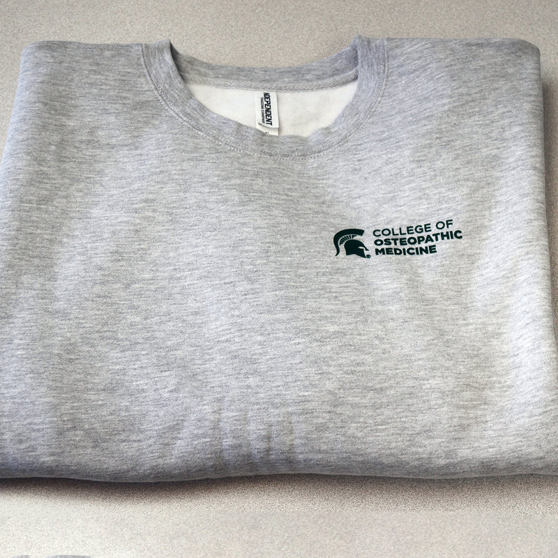 Front of heather gray crewneck sweatshirt with College of Osteopathic Medicine logo printed in forest green on the left side upper chest. 
