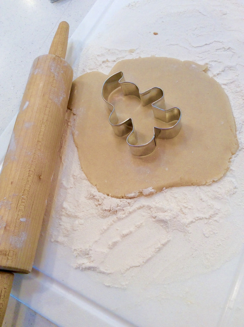 A rolling pin beside a Spartan-shaped cookie cutter on cookie dough.