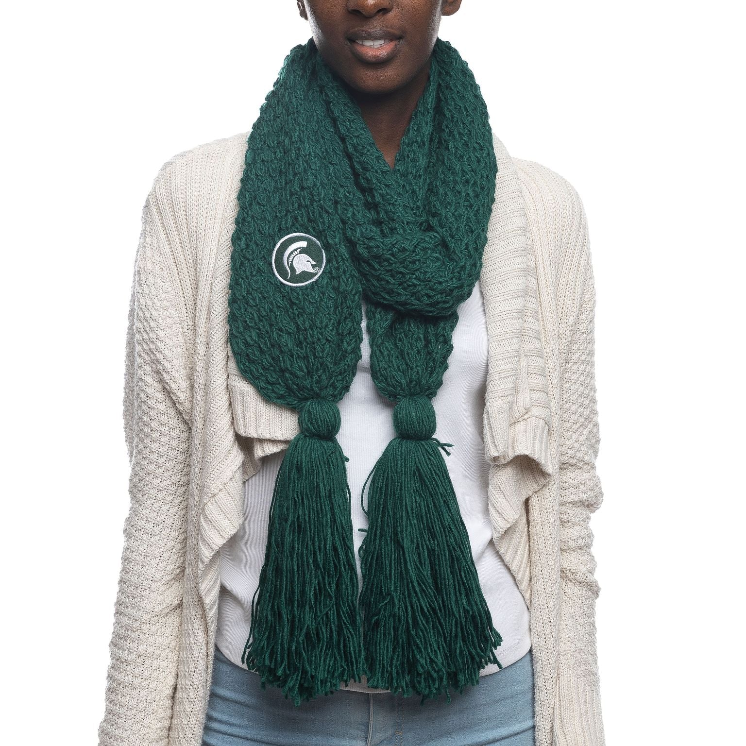 A green cable knit scarf with knots and tassels on the ends. On the left side is a green patch with a white embroidered Spartan Helmet logo.
