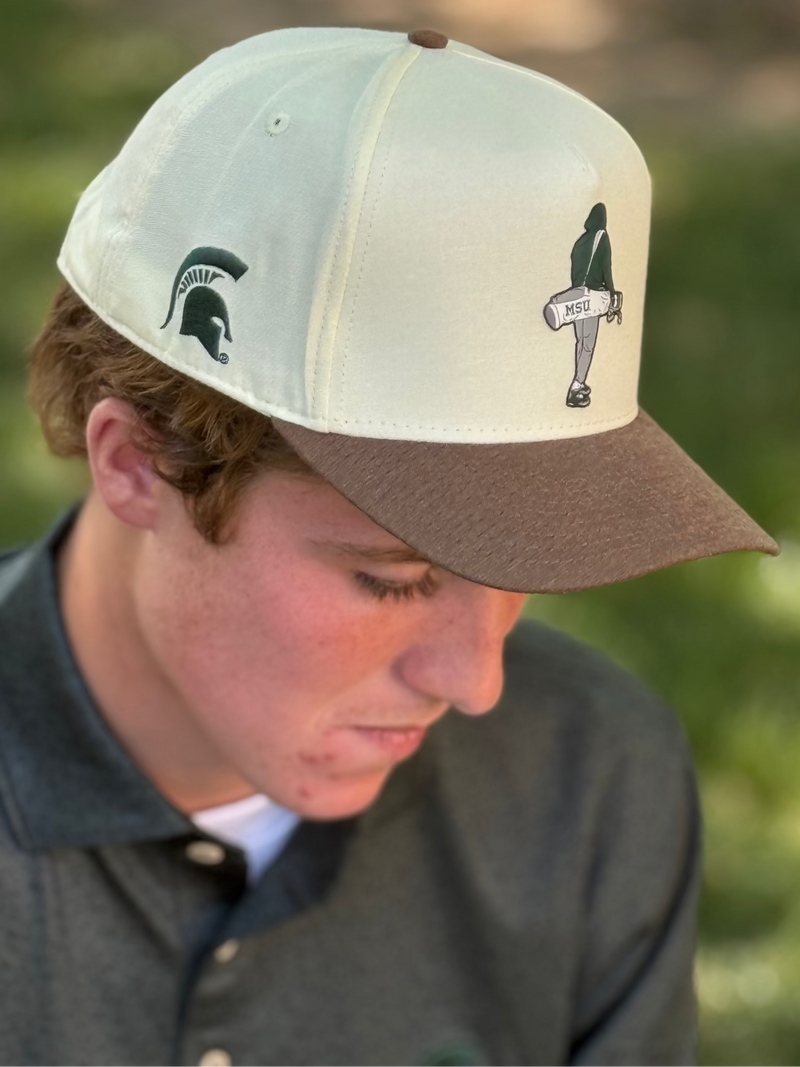 Person wearing a two-tone cap with logos outdoors