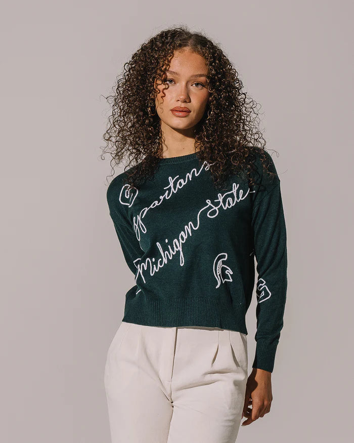 Woman wearing a green Michigan State sweater against a plain background
