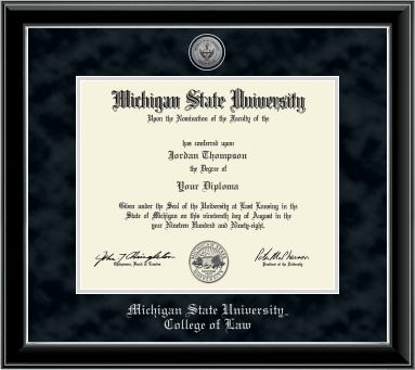 The diploma is enclosed in a black frame with silver accents and set against a black suede matte with silver outline around opening for diploma. Top of matting is silver engraved Law seal. Silver cursive letters is 'Michigan State University' at bottom. Below in silver cursive letters 'College of Law'.