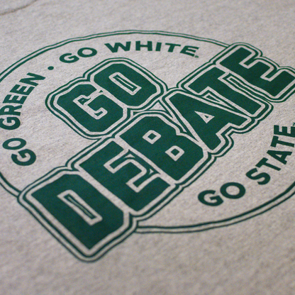 Close-up of a heather gray t-shirt featuring a green printed graphic that reads 'GO DEBATE' with 'GO GREEN . GO WHITE' and 'GO STATE' surrounding it.