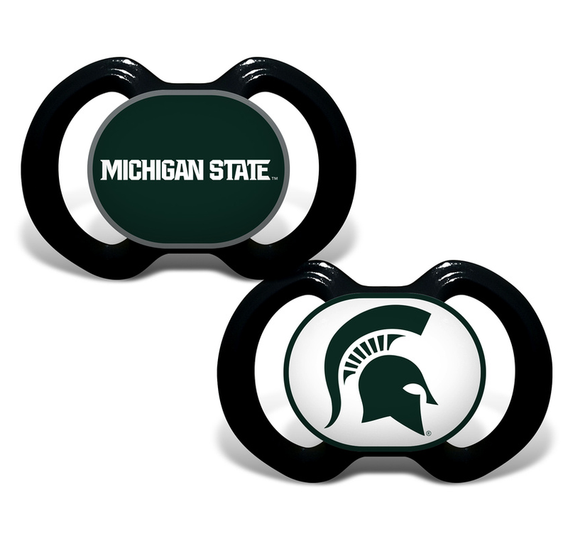 Two pacifiers. One has a black handle with a green button that reads "Michigan State" in white, and the other has a black handle with a white button featuring a green Spartan helmet.