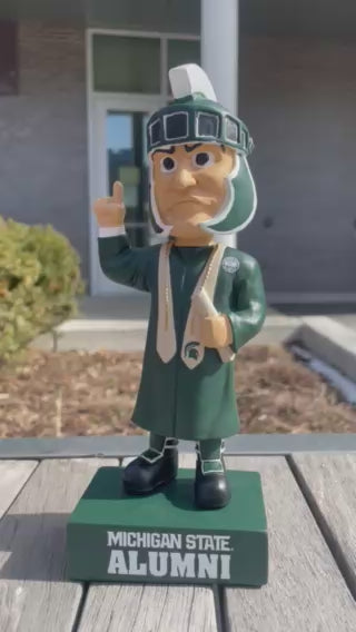 Video of a graduation Sparty bobblehead wearing graduation attire and featuring bold text that reads "Michigan State Alumni" base.
