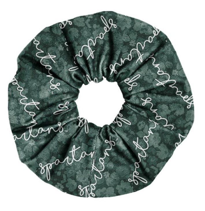 A green scrunchie-style hair tie with a floral pattern and patterned white cursive text that reads "Spartans." Shown on a white background. 